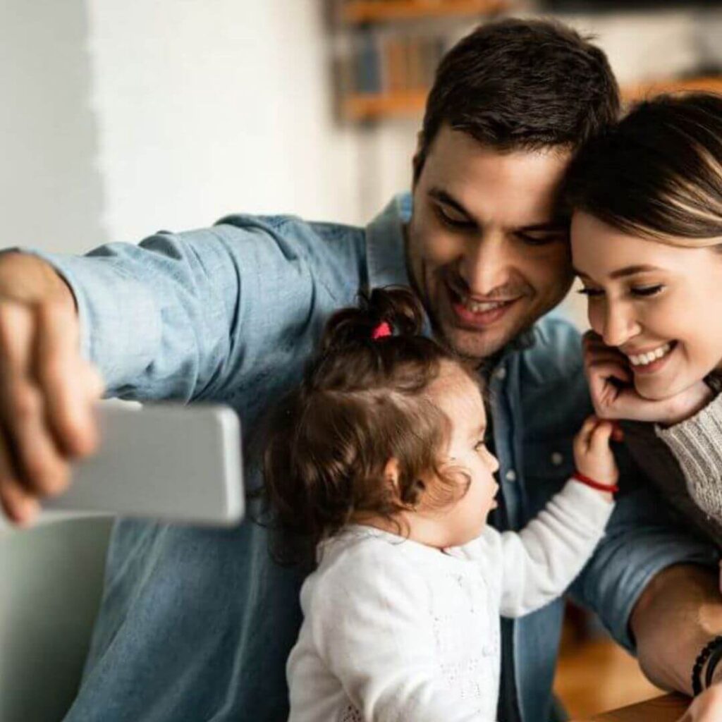 Proteção Financeira com Seguro de Vida pais-felizes-e-sua-filha-pequena-tirando-foto-em-casa